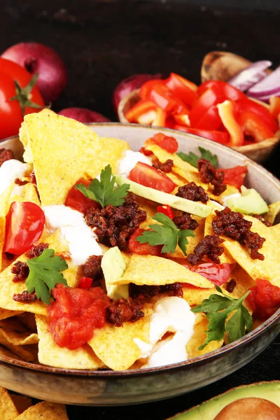 Mexican nacho chips garnished with ground beef, guacamole, melte — Stockfoto