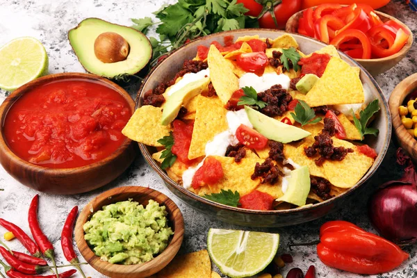 Mexican nacho chips garnished with ground beef, guacamole, melte — Stockfoto