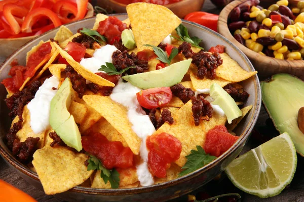 Mexican nacho chips garnished with ground beef, guacamole, melte — Stock Photo, Image