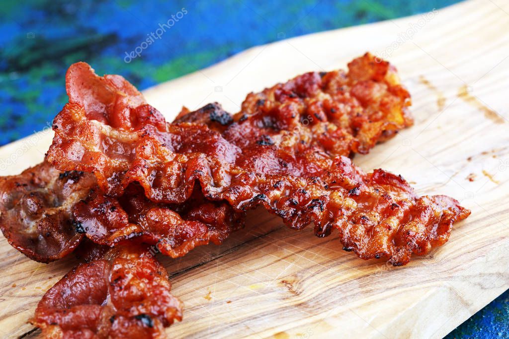 Closeup of slices of crispy hot freshly cooked bacon for tasty b