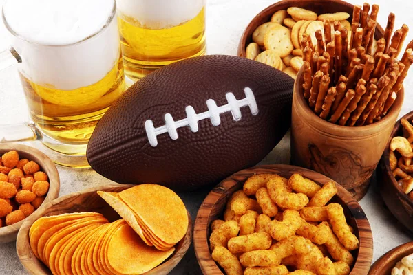Chips, salty snacks, football and Beer on a table. Great for Bow