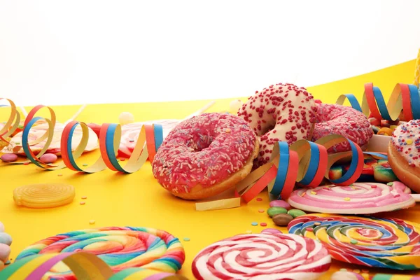 Sweet carnival donuts with streamer and confetti on yellow backg — Stock Photo, Image