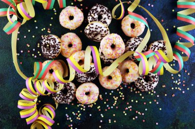 Renkli parti flamalarıyla donutlar ve köy arkaplanda konfeti.