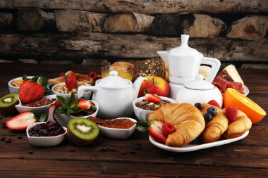 Kahvaltının yanında kahve, portakal suyu, kruvasan, mısır gevreği ve meyve var. Dengeli diyet. Granola ile Continental kahvaltı