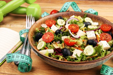 Taştan bir fincanda otantik taze salata, halterli egzersiz aletleri, bant ve çatal. Sağlıklı yaşam tarzları, sağlıklı sağlık kavramı. 