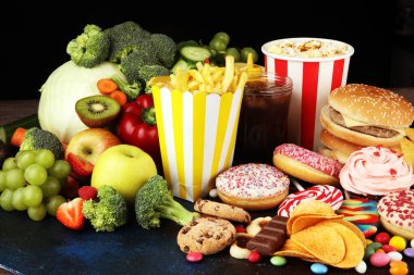 Sağlıklı ya da sağlıksız yiyecekler. Sağlıklı ve sağlıksız yiyeceklerin konsept fotoğrafı. Meyveler ve sebzeler karşısında donut, tatlı ve hamburger.