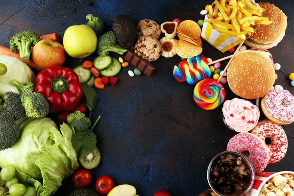 Sağlıklı ya da sağlıksız yiyecekler. Sağlıklı ve sağlıksız yiyeceklerin konsept fotoğrafı. Meyveler ve sebzeler karşısında donut, tatlı ve hamburger.