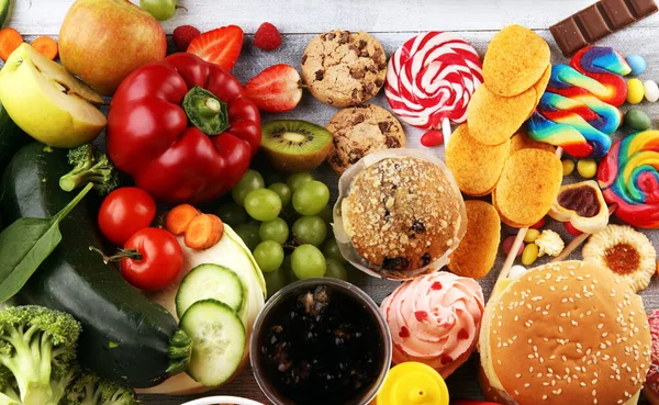 healthy or unhealthy food. Concept photo of healthy and unhealthy food. Fruits and vegetables vs donuts,sweets and burgers on table