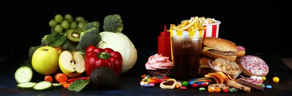 健康或不健康的食物 健康及不健康食物的概念照片 水果和蔬菜对着桌上的甜甜圈 糖果和汉堡包 — 图库照片