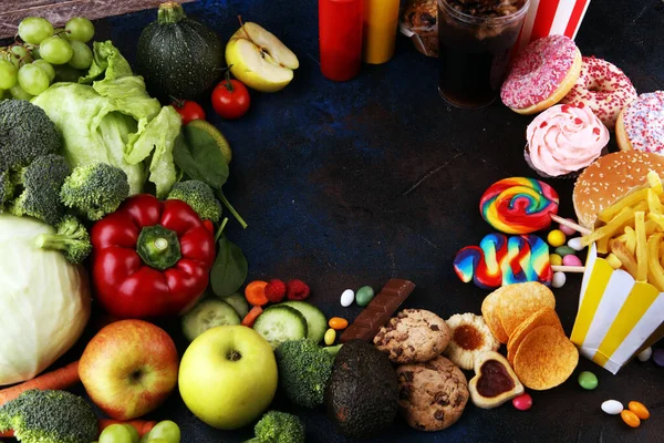 healthy or unhealthy food. Concept photo of healthy and unhealthy food. Fruits and vegetables vs donuts,sweets and burgers on table