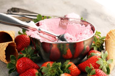 Çilekli dondurma kepçesi taze çilek ve kırsal bir arka planda dondurma külahları.