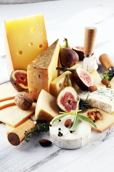 チーズプレートにはイチジクが添えられ 素朴なテーブルの上には様々なチーズが盛られています — ストック写真