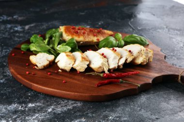 Kısmen dilimlenmiş ızgara tavuk göğsü. Köy arka planında kesim tahtası.