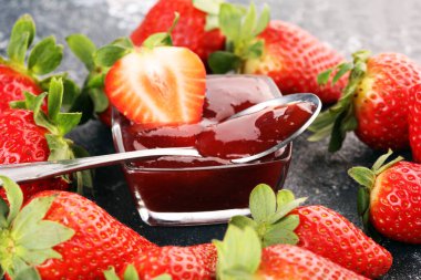 Çilek reçeli cam kavanozda, çilekli ve yapraklı. Ev yapımı çilekli marmelat ve meyve.