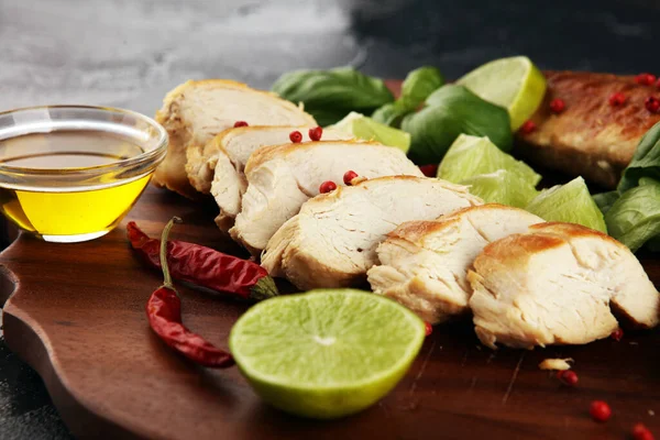 Partially sliced grilled chicken breast on cutting board on rustic background