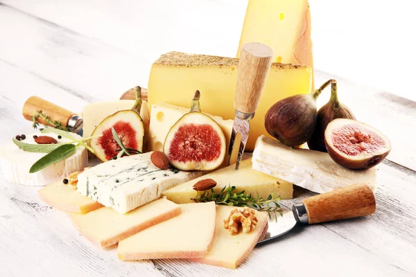 チーズプレートにはイチジクが添えられ 素朴なテーブルの上には様々なチーズが盛られています — ストック写真