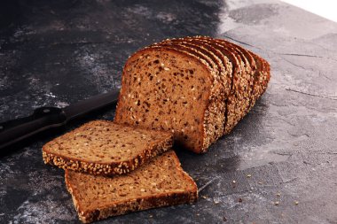 Kesme tahtasında dilimlenmiş çavdar ekmeği. Köy arka planında tohumlu tam tahıllı çavdar ekmeği.