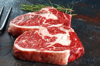 İki taze pirzola bifteği, Rosmary ve kırsal bir arka plan.