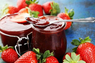 Çilek reçeli cam kavanozda, çilekli ve yapraklı. Ev yapımı çilekli marmelat ve meyve.