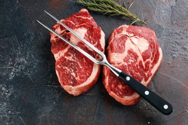 İki taze pirzola bifteği, Rosmary ve kırsal bir arka plan.