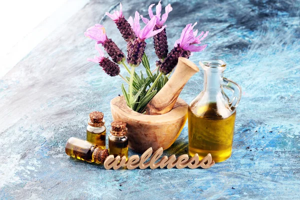 lavender herbal oil and lavender flowers. bottle of lavender massage oil for aromatherapy beauty treatment and wellness letters made of wood