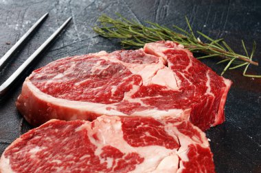 İki taze pirzola bifteği, Rosmary ve kırsal bir arka plan.