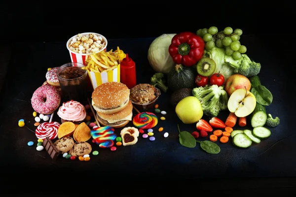 healthy or unhealthy food. Concept photo of healthy and unhealthy food. Fruits and vegetables vs donuts,sweets and burgers on table