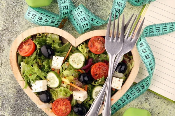 真正新鲜的沙拉在木制心形杯子与哑铃锻炼设备 测量磁带在桌子上 健康的生活方式 健康的概念和新鲜的配料 — 图库照片