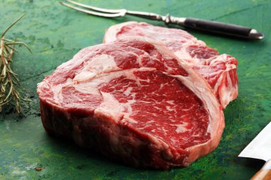 İki taze pirzola bifteği, Rosmary ve kırsal bir arka plan.