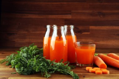 Şişe içinde taze havuç suyu ve kırsal masada organik havuç.