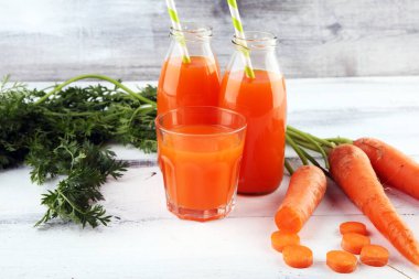 Şişe içinde taze havuç suyu ve kırsal masada organik havuç.