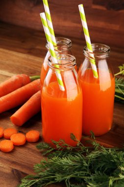 Şişe içinde taze havuç suyu ve kırsal masada organik havuç.