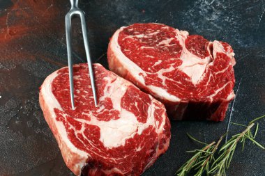 İki taze pirzola bifteği, Rosmary ve kırsal bir arka plan.