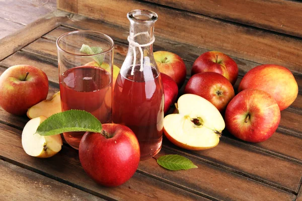 Apple cider drink and apples with leaves on rustic table