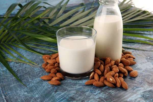 新鮮なナッツとヤシの葉を背景にアーモンドミルク アーモンドビーガン乳製品 — ストック写真
