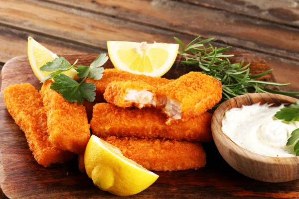 fresh fish fingers with remoulade sauce. breaded fish fingers with lemon