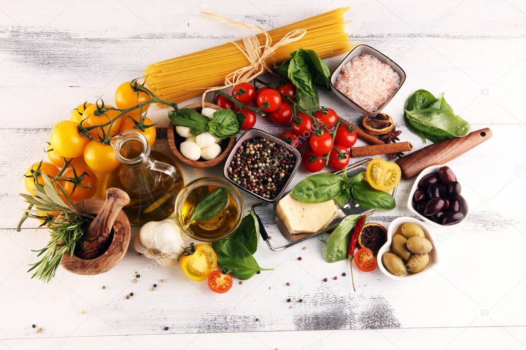 Italian food background with herbs and spices, vine tomatoes, basil, spaghetti, olives, parmesan, olive oil, garlic, peppercorns and rosemary