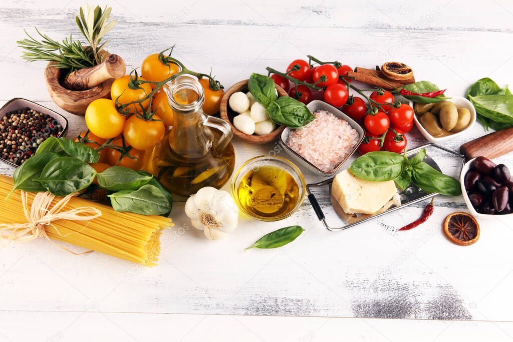 Italian food background with herbs and spices, vine tomatoes, basil, spaghetti, olives, parmesan, olive oil, garlic, peppercorns and rosemary