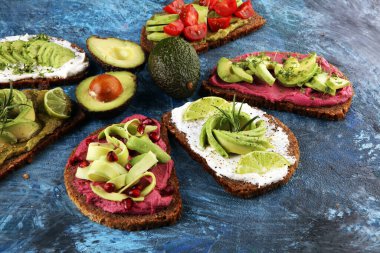 Avokado tostu. Avokado ve domates ve pancar gibi malzemelerle sağlıklı çavdarlı sandviç çeşitleri.