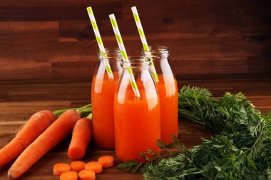 Şişe içinde taze havuç suyu ve kırsal masada organik havuç.