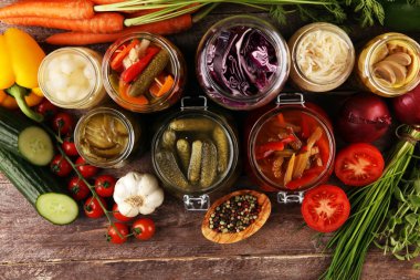 Sebzeleri cam kavanozlarda saklar. Salatalık turşusu, havuç, mayalanmış lahana ve soğan.