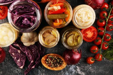 Sebzeleri cam kavanozlarda saklar. Salatalık turşusu, havuç, mayalanmış lahana ve soğan.