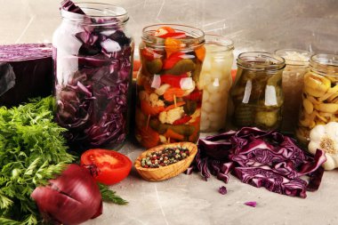 Sebzeleri cam kavanozlarda saklar. Salatalık turşusu, havuç, mayalanmış lahana ve soğan.