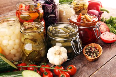 Sebzeleri cam kavanozlarda saklar. Salatalık turşusu, havuç, mayalanmış lahana ve soğan.