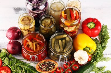 Sebzeleri cam kavanozlarda saklar. Salatalık turşusu, havuç, mayalanmış lahana ve soğan.