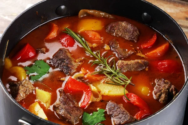 Meat stew with vegetables. Beef stew with potatoes, carrots and herbs on table.