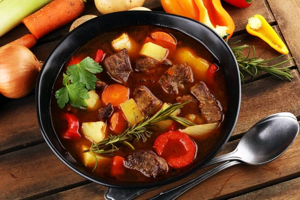 Meat stew with vegetables. Beef stew with potatoes, carrots and herbs on table.