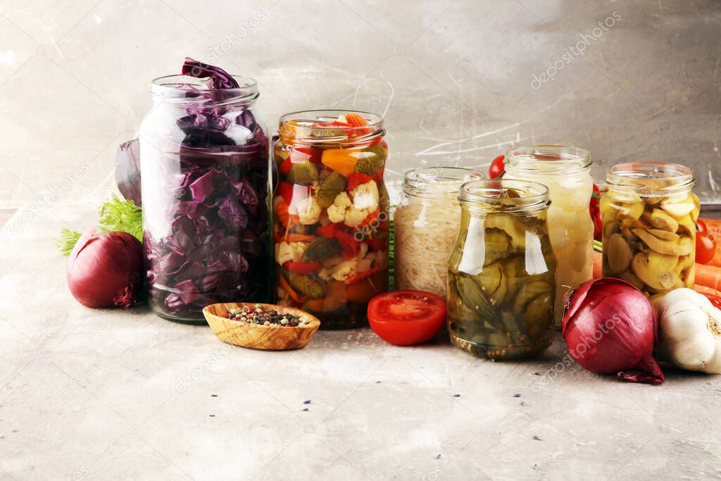 Preserves vegetables in glass jars. Pickled Cucumber, carrot, fermented cabbage and onions on rustic table