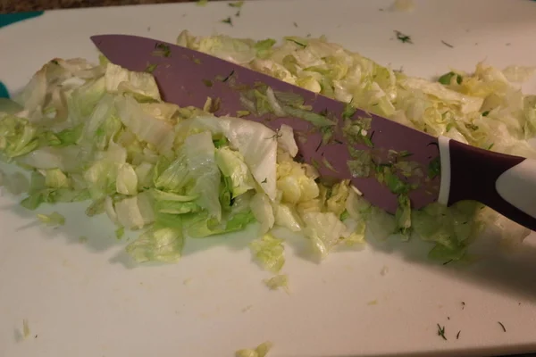 Iceberg lettuce being chopped up on a cutting board — Stock Photo, Image