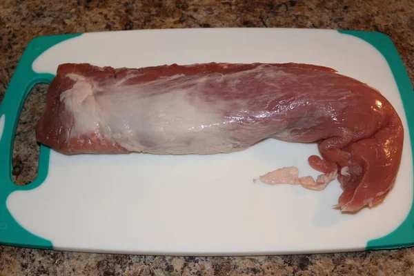 Kesme tahtasındaki çiğ domuz filetosu pişirmeye hazır.